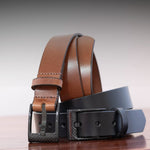 Brown and black leather belts on a wooden surface with a neutral background